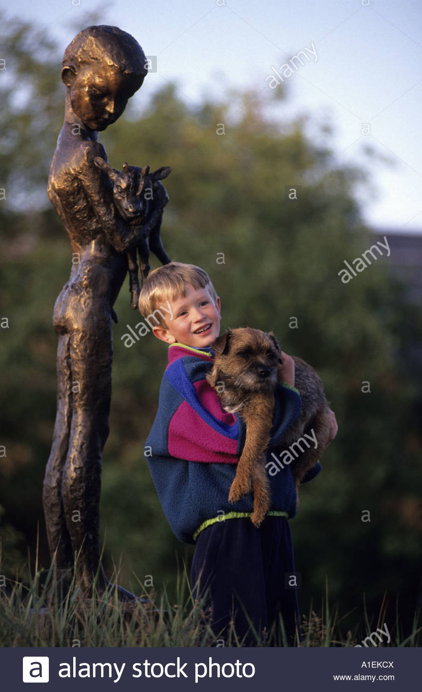 a-boy-holding-a-dog-in-his-lap-in-front-of-a-statue-A1EKCX.jpg